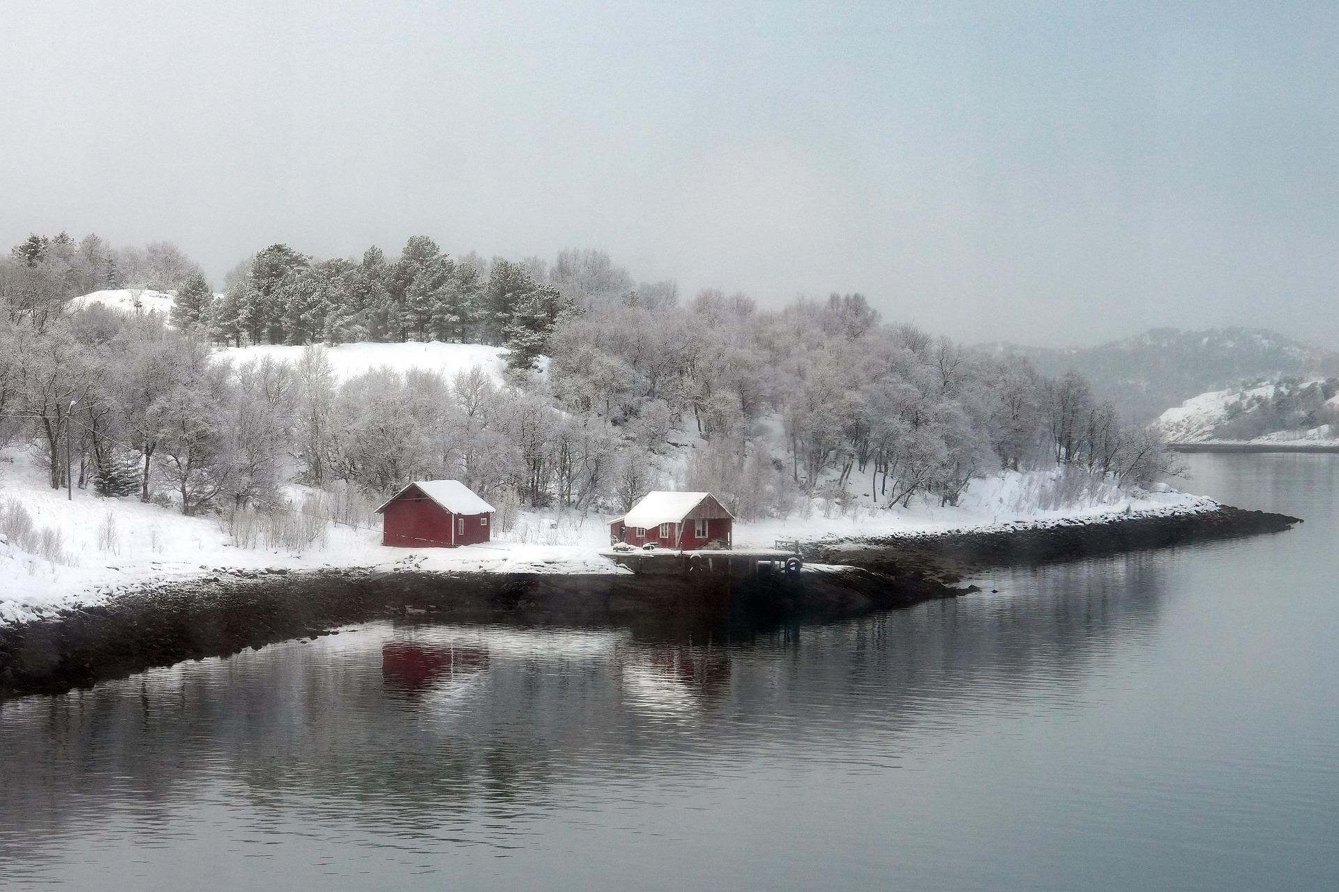 Set along the शांत and icy shores of Norwegian Fjords in Norway, Makabera Fjord is a winter wonderland of snow-covered forests, calm reflective waters, and charming red cabins. This tranquil landscape captures the raw beauty of the Nordic wilderness, offering a peaceful and picturesque escape into nature.